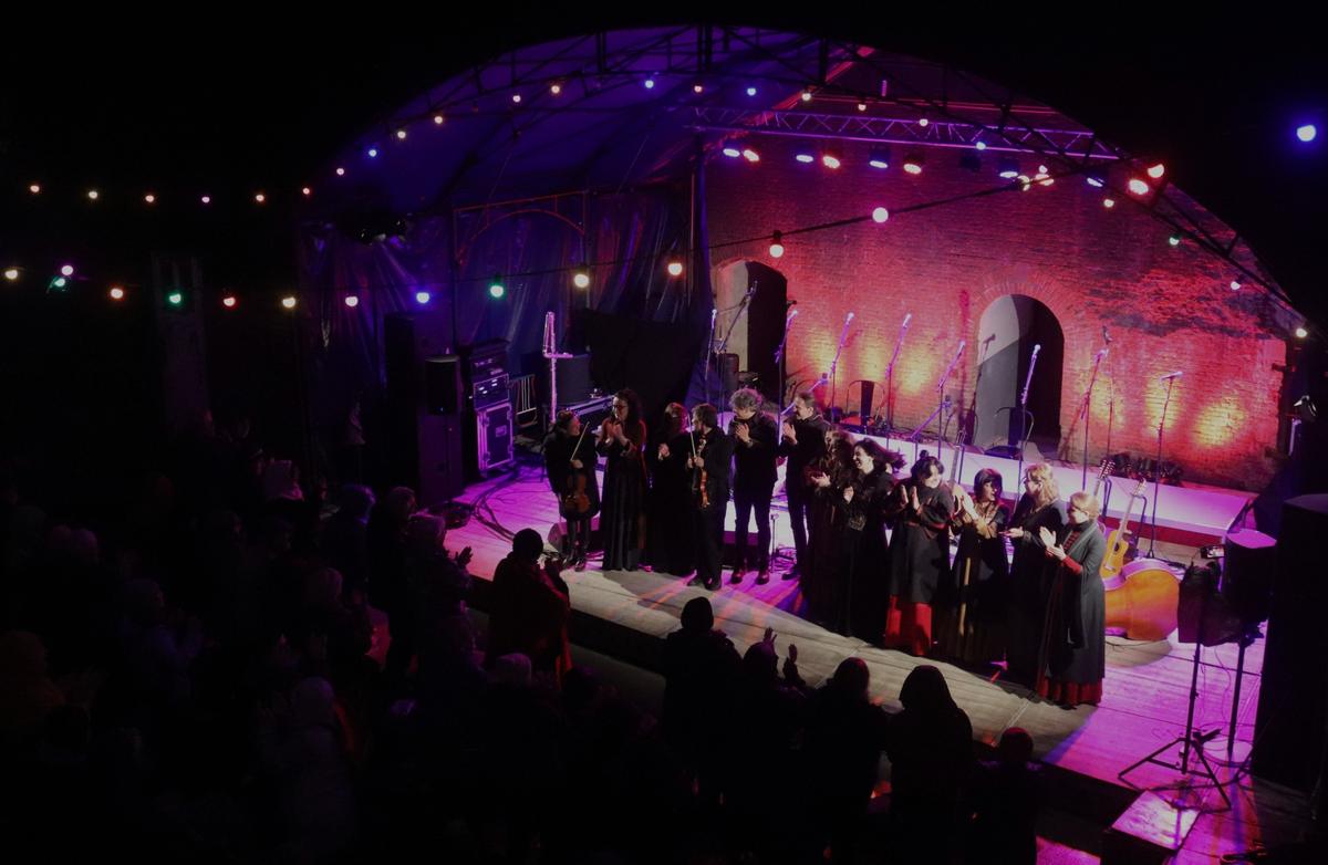 Muzikanten nemen applaus in ontvangst op een openluchtpodium bij avond